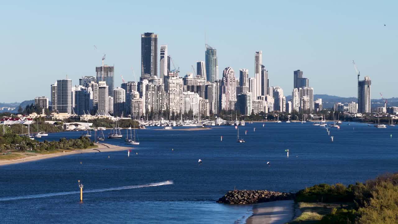 Drone footage captures Gold Coast's skyline and waterways during sunset, highlighting boats and cityscape under warm lighting