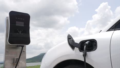 Progressive-concept-of-EV-car-with-green-field,-hill-and-lake-as-background.