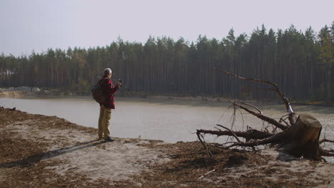 comunicación y unidad con la naturaleza hombre de mediana edad está disfrutando y admirando la naturaleza del río y el bosque en un soleado día de otoño