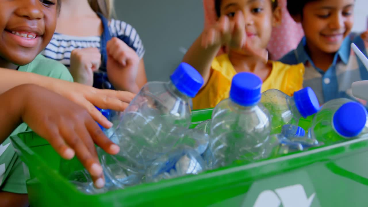 escolares poniendo botellas en contenedores de reciclaje en el escritorio en el aula 4k