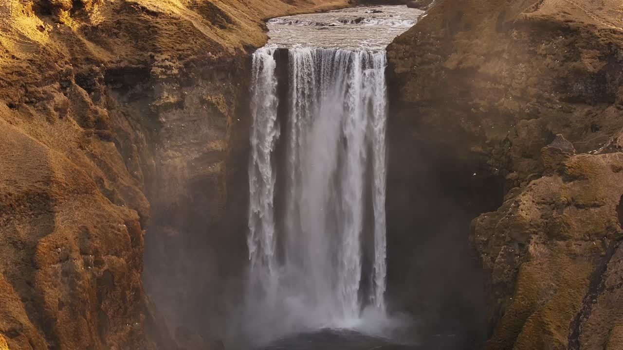 Majestic Skógafoss waterfall in Iceland plunges powerfully between rocky cliffs. Mist rises from the Skógá River. Ideal for nature, travel, and awe-inspiring visuals.