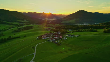 Drone-Aéreo-Girando-Sobre-Un-Pequeño-Pueblo-En-Un-Valle-Con-Una-Cadena-Montañosa-Rodeando-Por-Todos-Lados-En-Noruega-Al-Amanecer