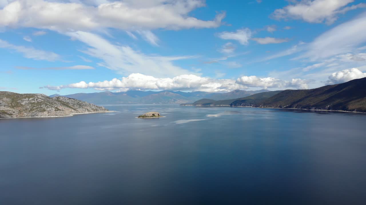 pequeña isla rocosa en medio del lago prespa rodeada de montañas en un día nublado