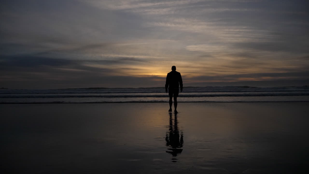 hombre en la playa al amanecer en la costa de california