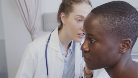 diverse female patient and doctor inspecting her ear in hospital, in slow motion