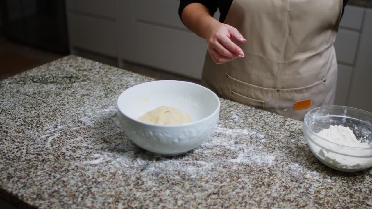 High angle view of adding bread dough to a bowl, covering it on a flour-dusted counter. Slow Motion