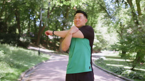 japanese sporty healthy man athlete in park outdoors stretching hands stretch arms morning workout