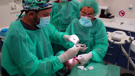 equipo de dentistas cosiendo la boca de un paciente anestesiado
