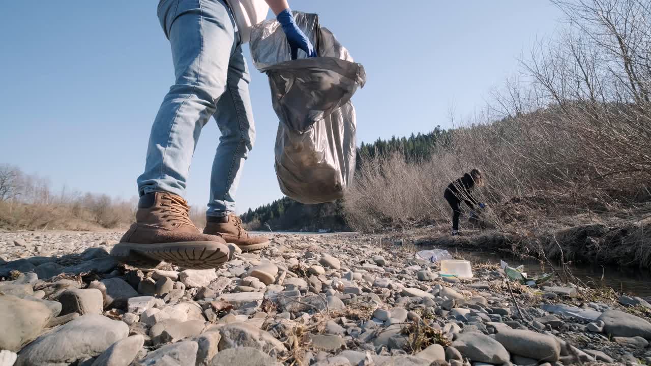 trabajo en equipo limpiando plástico en la playa. voluntarios recogen basura en una bolsa de basura. contaminación plástica y concepto de problema ambiental. limpieza voluntaria de la naturaleza del plástico. ecologización del planeta