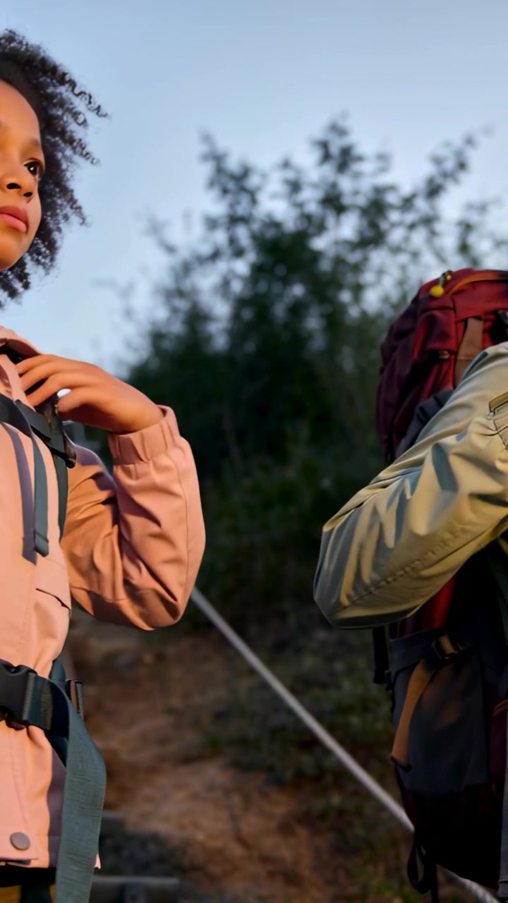 Vertical video: Tightening straps, child and guardian securing backpacks on hiking trail to climb