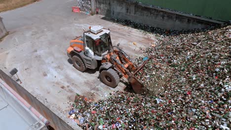 Gabelstaplerbagger-Greift-Nach-Glas,-Hochleistungsmaschine-Verfügt-über-Einen-Langen-Arm-Mit-Einer-Glasgreifvorrichtung,-Drohnen-Luftaufnahme,-Glasrecyclingkonzept