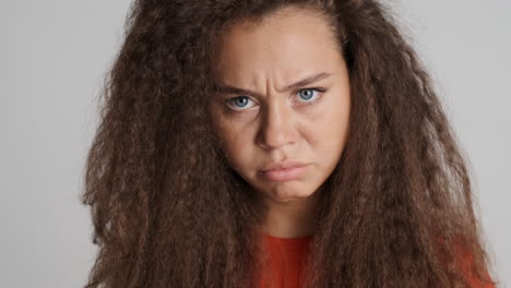 angry caucasian curly haired woman looking to the camera.