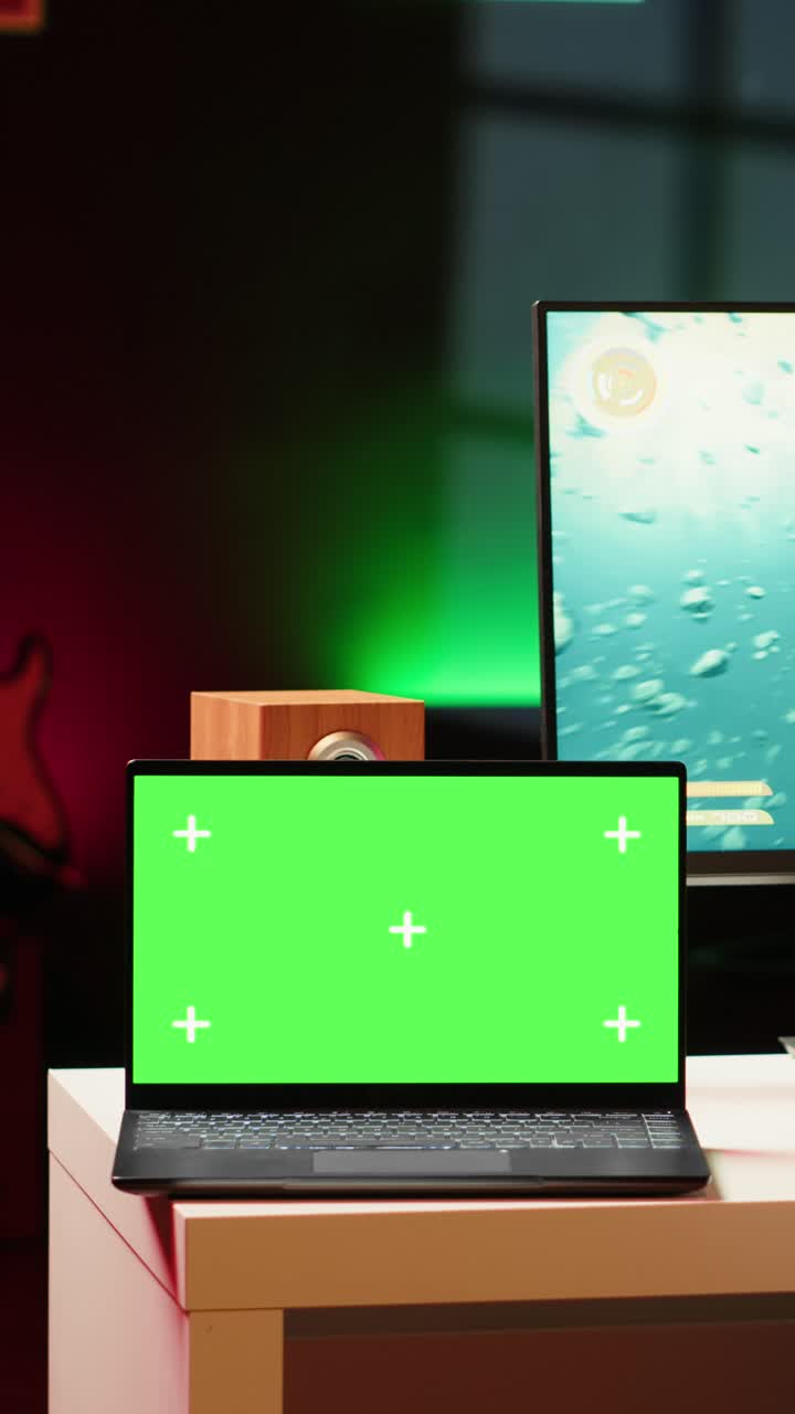 Mockup di video verticale di un laptop su una scrivania accanto a un uomo che gioca a un videogioco SF