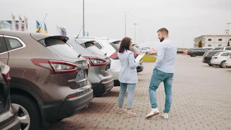 una pareja revisando coches en un concesionario