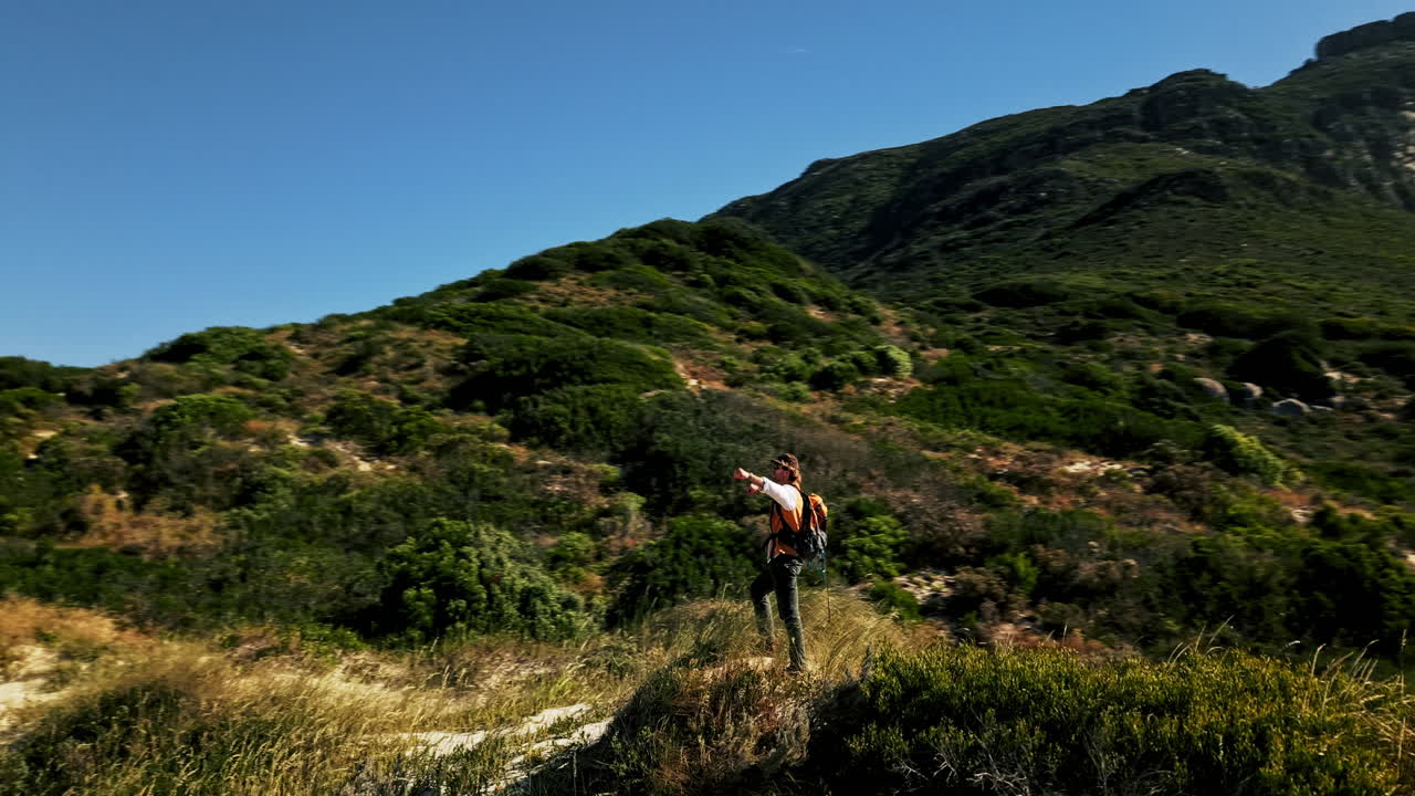 Uomo con zaino in piedi su una montagna che si affaccia sull'oceano