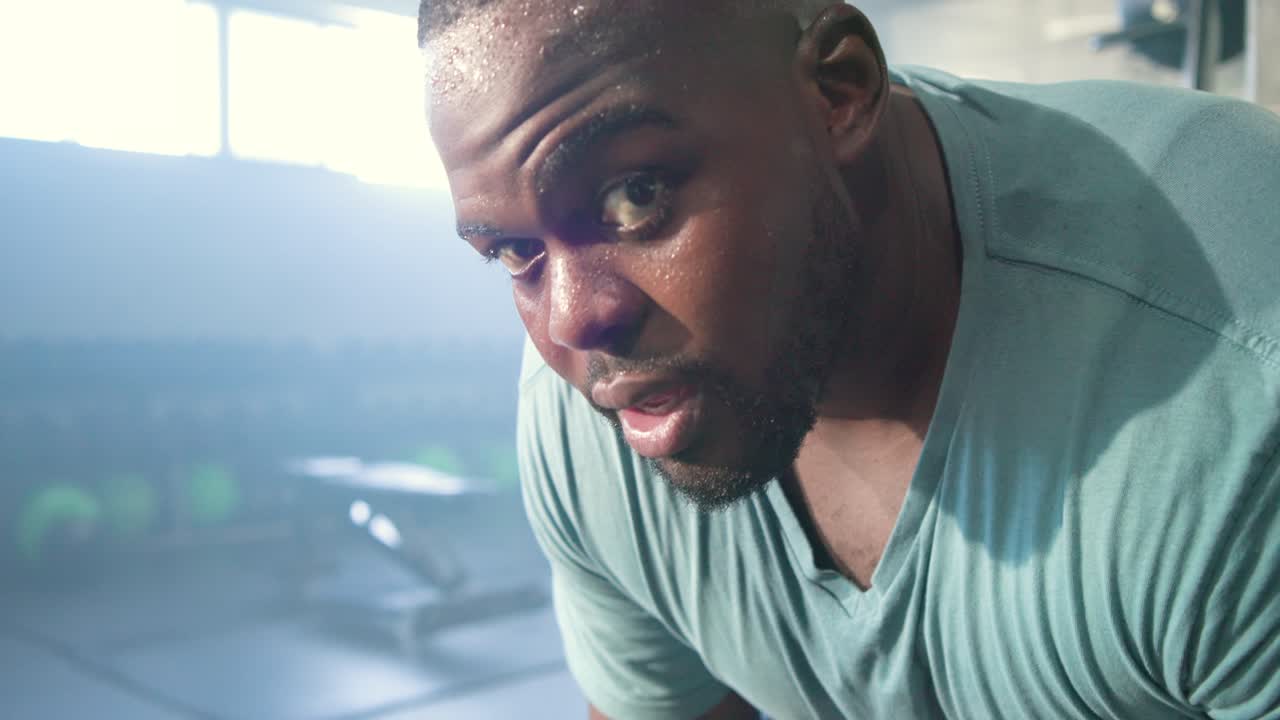 African man in teal shirt recovering from intense workout, lifting head and meeting camera gaze