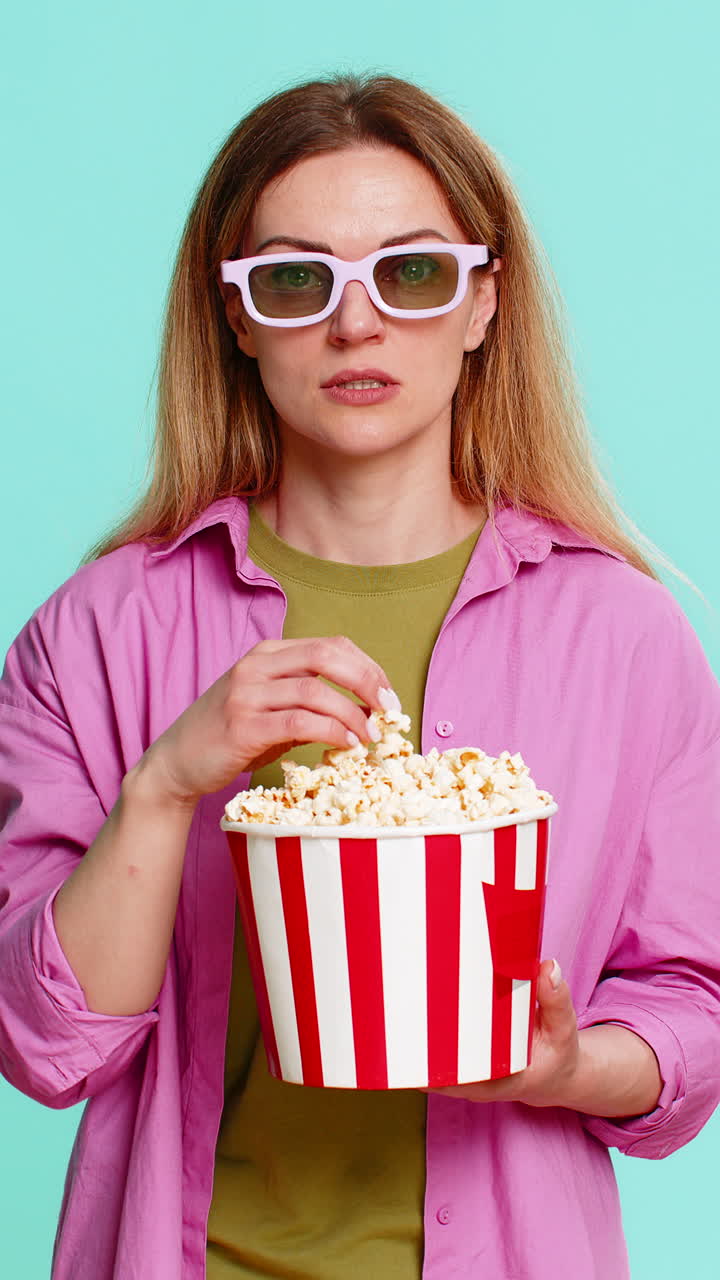 Adult woman in 3d glasses eating popcorn watching exciting movie with intense surprising storyline