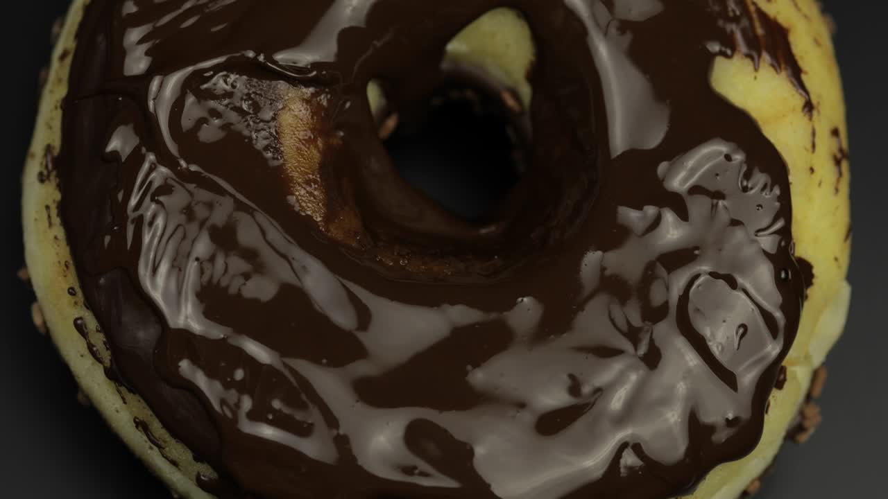 el dedo de la mujer toca el chocolate oscuro derretido en una deliciosa rosquilla