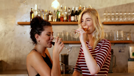 Female-friends-happily-hugging-each-other-while-having-drinks-at-bar-4K-4k