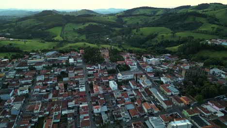 aerial view of a city surrounded by green hills, with several residential buildings arranged in organized streets, there is vegetation that stretches across the horizon, contrasting with the city.