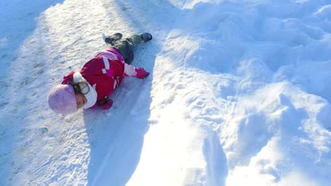 Kleines-Mädchen-Liegt-Auf-Schnee.-Unbeschwertes-Kind,-Das-Im-Schnee-Spielt