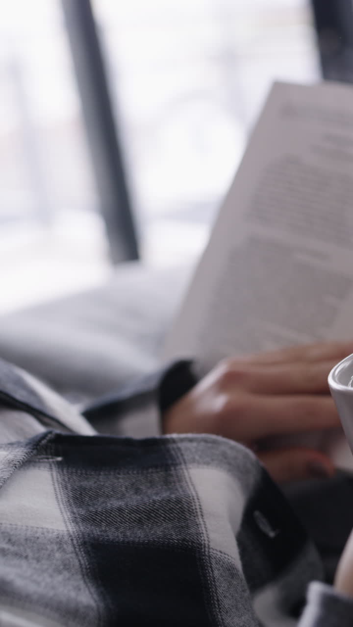 Relaxed Person Reading a Book and Drinking from a Mug