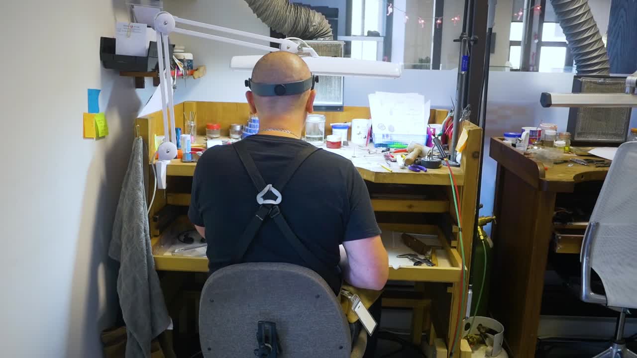 male jewelry maker hand polishing and buffing a silver ring in a jewellery making workshop