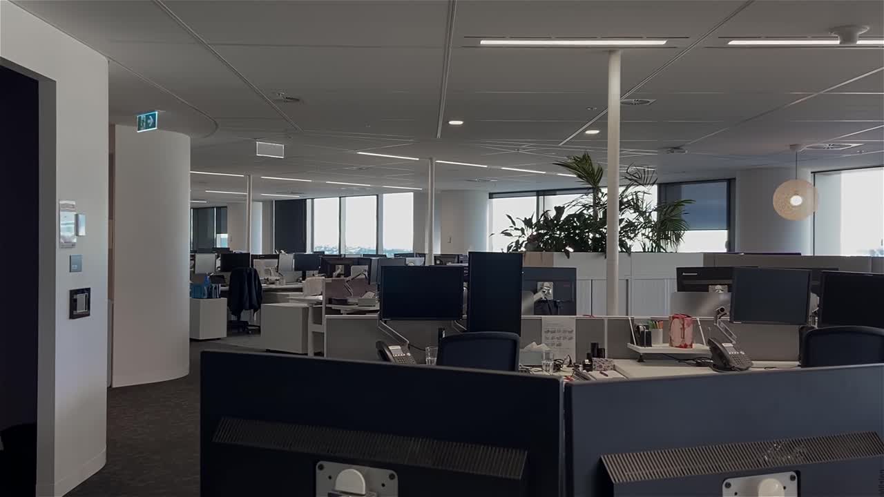 High quality dolly shot over empty desks in a large and deserted office building with unattended workstations, during the COVID-19 pandemic lockdown, with all employees working from home