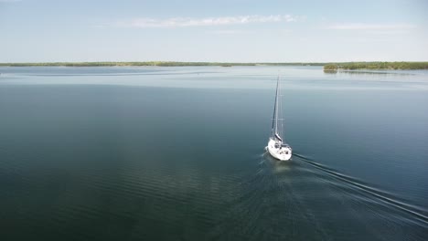 aerial of lone sailboat heading out with calm water, hessel, michigan