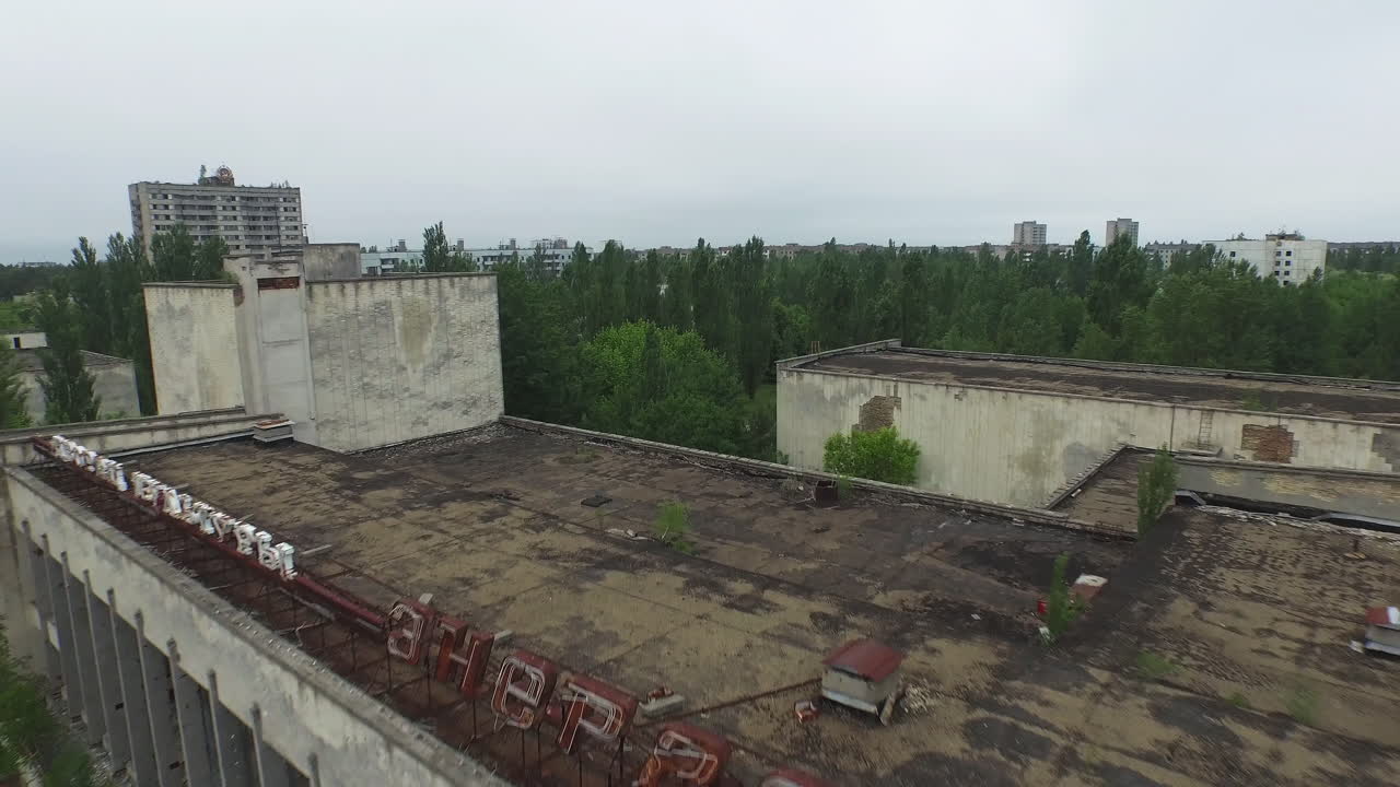 Aerial view of Pripyat's abandoned Palace of Culture Energetik. Decaying concrete structures are reclaimed by abundant foliage, illustrating the passage of time since the disaster. A haunting perspect