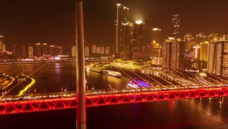 aerial: twin river bridges at night in chongqing with cityscape and skyscrapers, yuzhong district, china, crane down drone shot