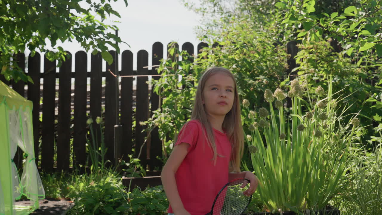 Caucasian Girl Receiving Racket In Garden Learning Moment, Closeup Exchange Of Coachlike Guidance, Curious Expression, Green Foliage And Wooden Fence Backdrop, Gentle Teaching Vibe