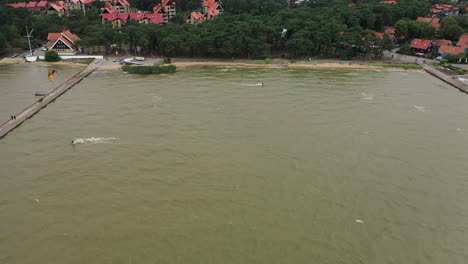 AERIAL:-Active-People-Practicing-Kite-Surfing-and-Windsurfing-on-a-Cloudy-Day