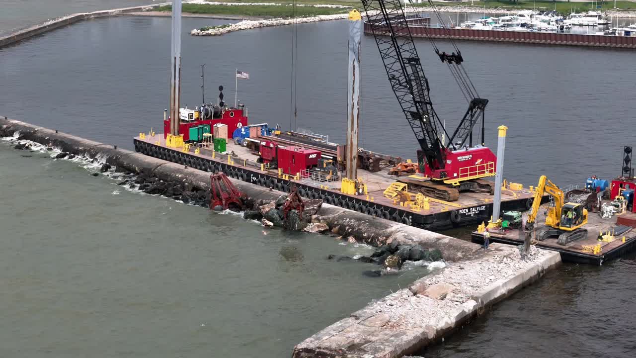 Using a grapple, a crane moves pieces of riprap to build up a pier in Algoma, WI on Lake Michigan