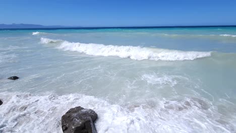 Panoramic-shot-of-shoreline-with-cliffs-splashed-by-white-waves-and-blue-turquoise-sea-background-in-Albania