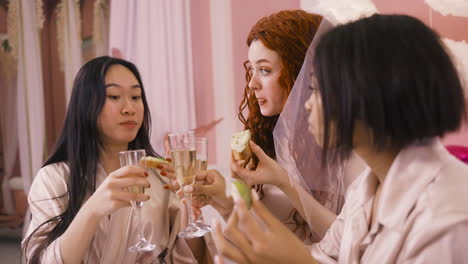 Side-View-Of-Three-Multiethnic-Friends-Drinking-Champagne-And-Eating-Food-Celebrating-Bachelorette-Party