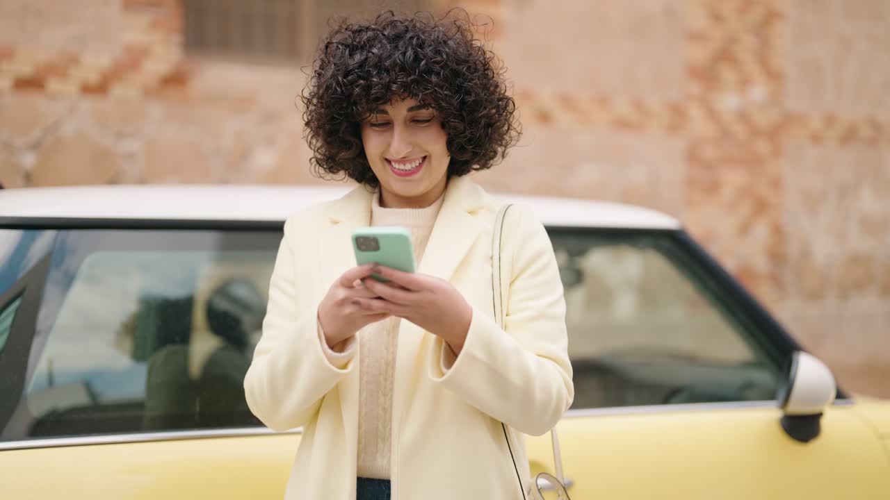 una mujer joven sonriendo con confianza usando un teléfono inteligente en la calle