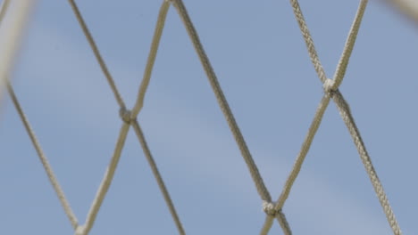 macro close-up of a piece of goal netting - swaying in the wind against a backdrop of blue sky