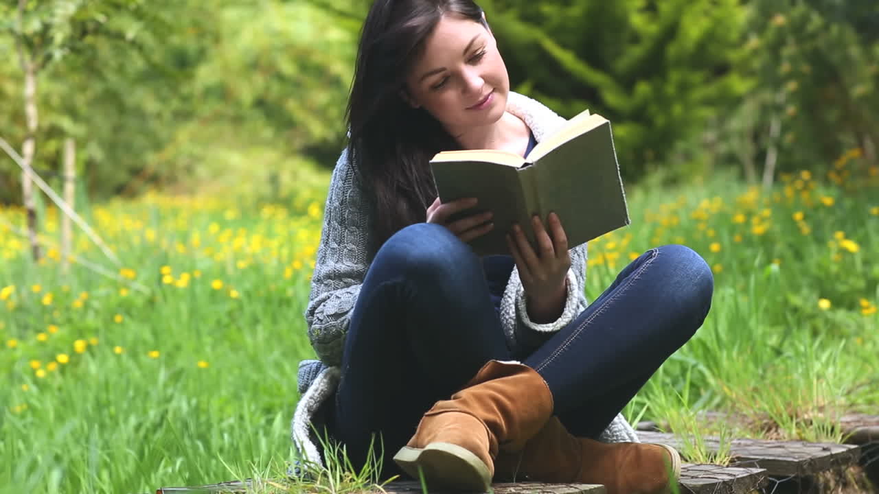 mujer sentada en la hierba leyendo un libro