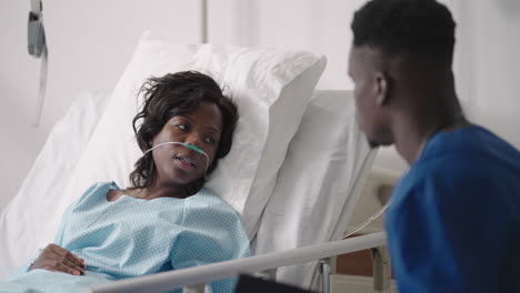 a young african-american male doctor is talking to a patient. a black woman patient talks to a doctor