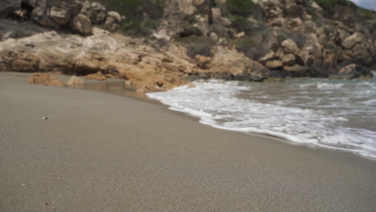 Olas rompiendo en la orilla junto a una roca en cámara lenta