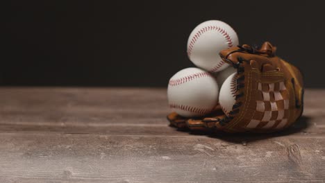 close up studio baseball still life with balls in catchers mitt on wooden floor 1