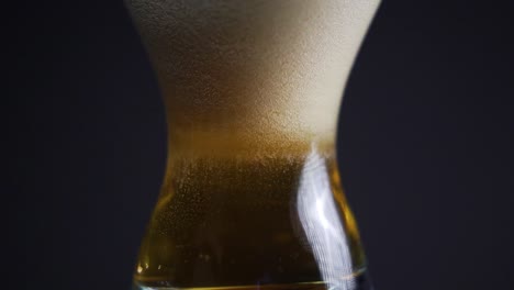 beer bubbles in full glass of beer forming up carbonation through tulip glass in dark studio slow motion carbonation product video