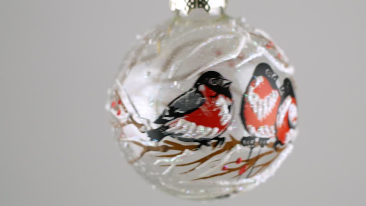 Golden Christmas ball toy turning round and back in luminous light on dark green background. New Year pattern.