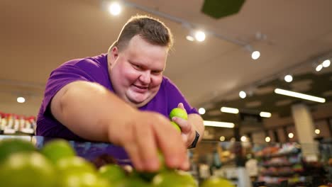 Glücklicher-übergewichtiger-Mann,-Der-Limetten-Von-Der-Theke-In-Die-Hand-Pflückt.-Ein-übergewichtiger-Mann,-Der-Ein-Lila-T-Shirt-Trägt,-Verzichtet-Auf-Plastiktaschen-Und-Nimmt-Sie-Mit.-Maßnahmen-Zur-Verbesserung-Der-Umwelt