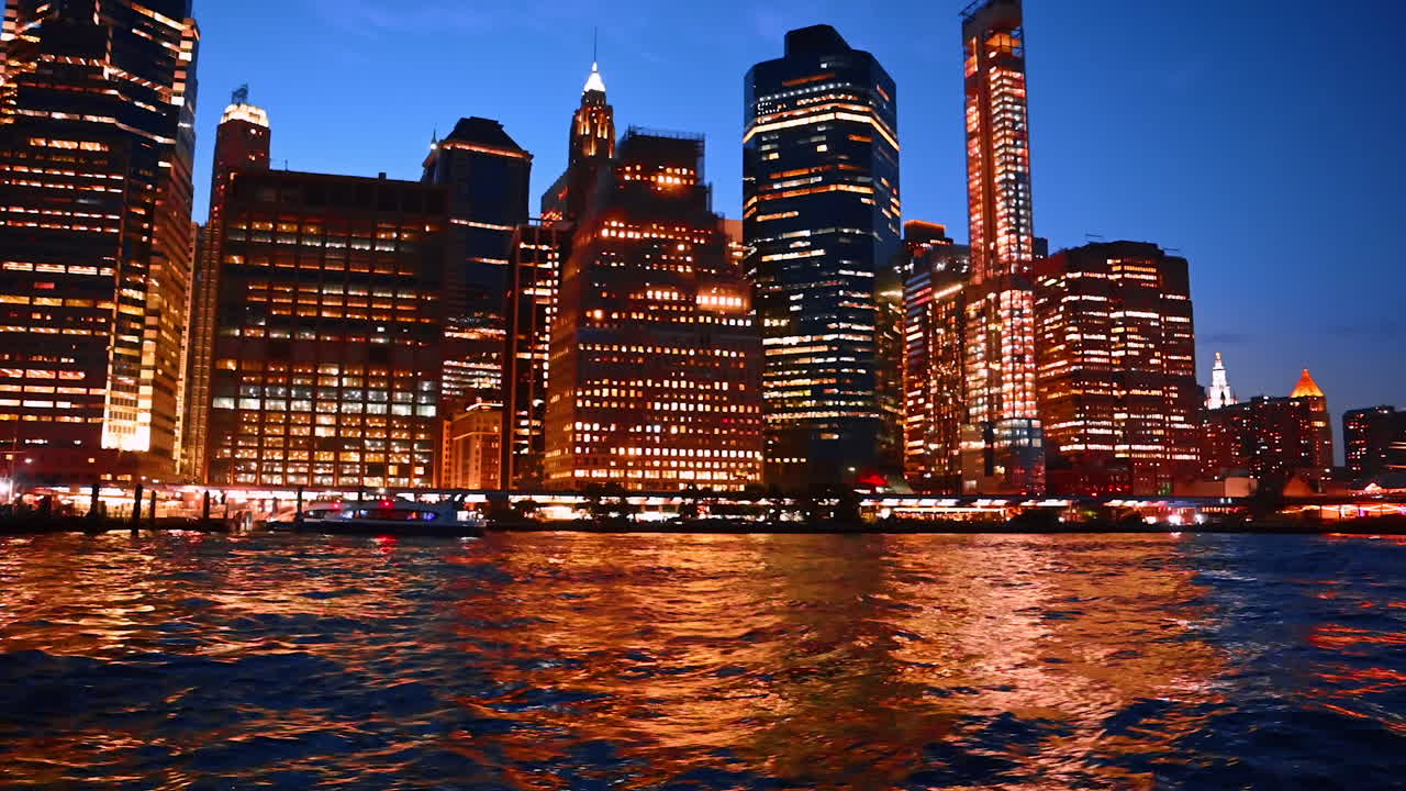 Brilliant illumination of night New York reflecting in the East River waterscape. Watching the skyline of metropolis from the boat