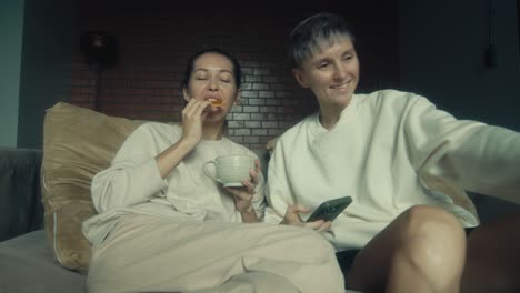 two women relaxing and enjoying coffee and snacks at home