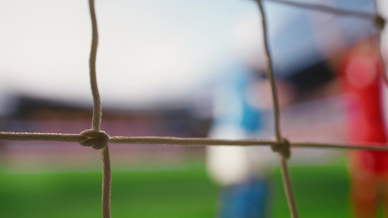Selective focus of soccer ball crossing line of goal frame on pitch