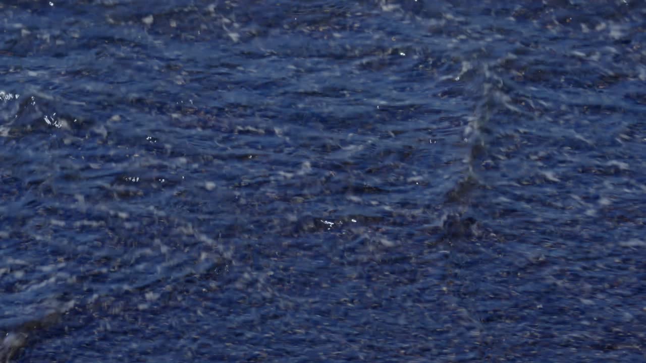 Dark ocean waves crashing over scenic beach made of volcano black sand in Santorini Greece