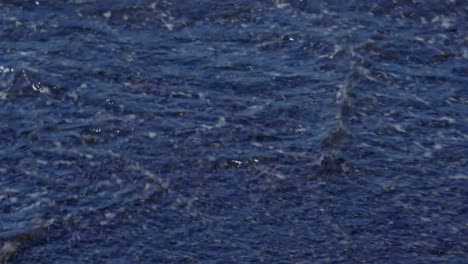 dark ocean waves crashing over scenic beach made of volcano black sand in santorini greece